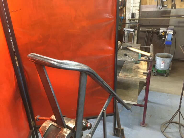 Formed metal cap rail in a shop with a welding curtain behind