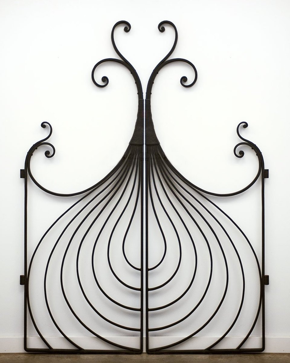 Wrought iron onion gate with curving bars and scrolled finials against a white wall