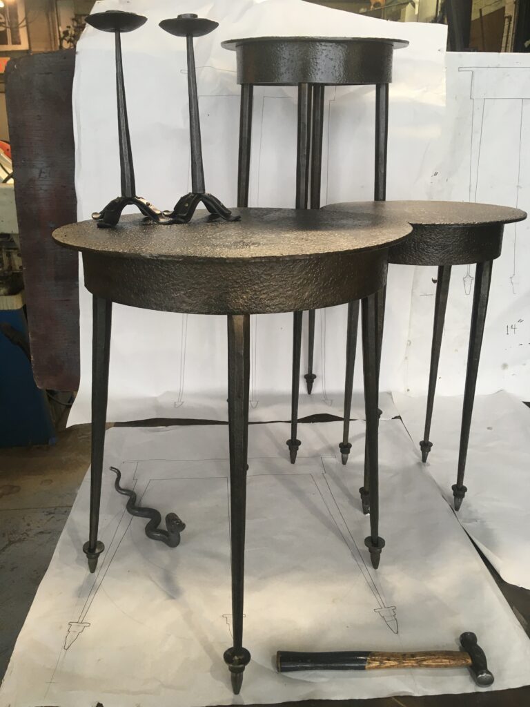 Set of forged metal end tables with round tops on tapered legs