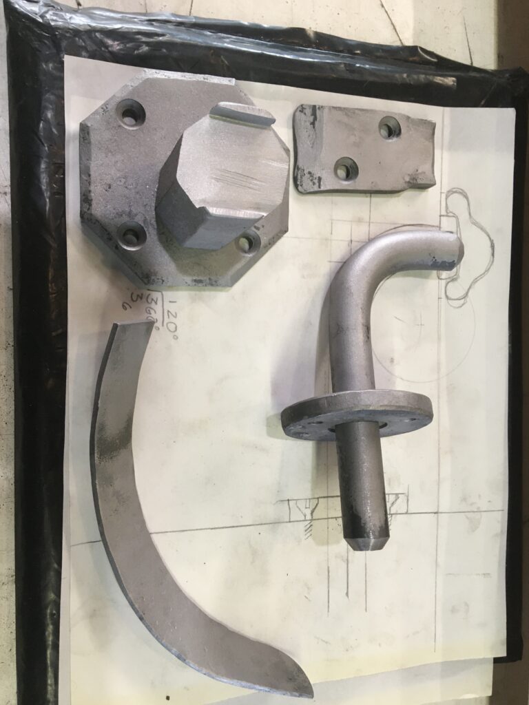 Forged handrail bracket parts laid out on a full-size drawing
