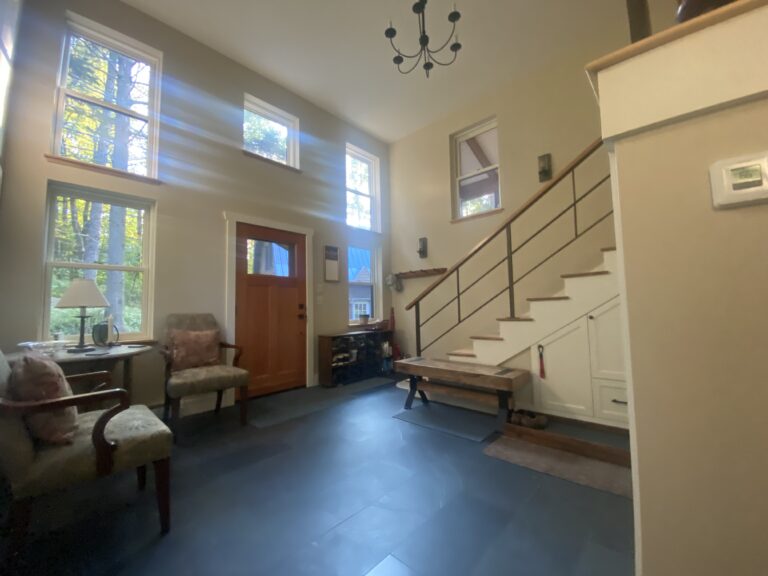 Slim metal handrail along a stair in a high-ceilinged entry hall
