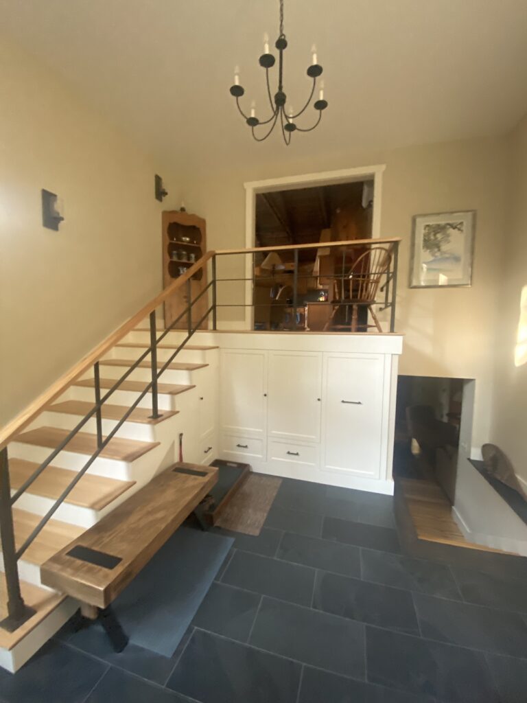 Forged metal handrail rising along a stair beside a landing in an entry hall