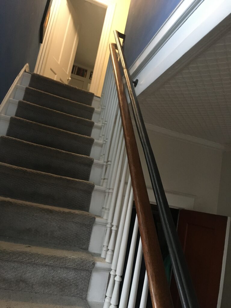 Dark wood handrail with white balusters along a carpeted staircase