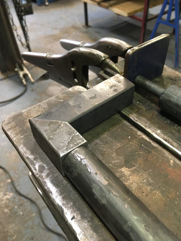 Metal bars clamped in a vise on a shop bench