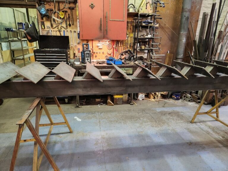Steel stair stringer with tread brackets laid on stands in the shop