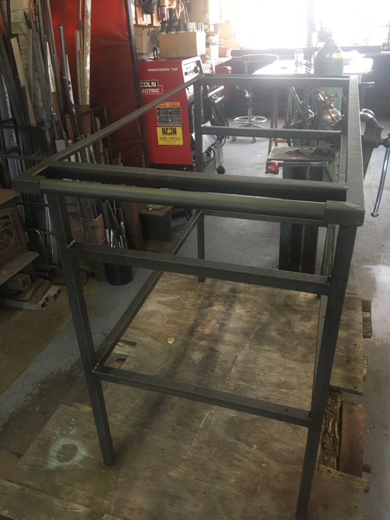 Welded steel vanity frame with a towel bar in a metal shop