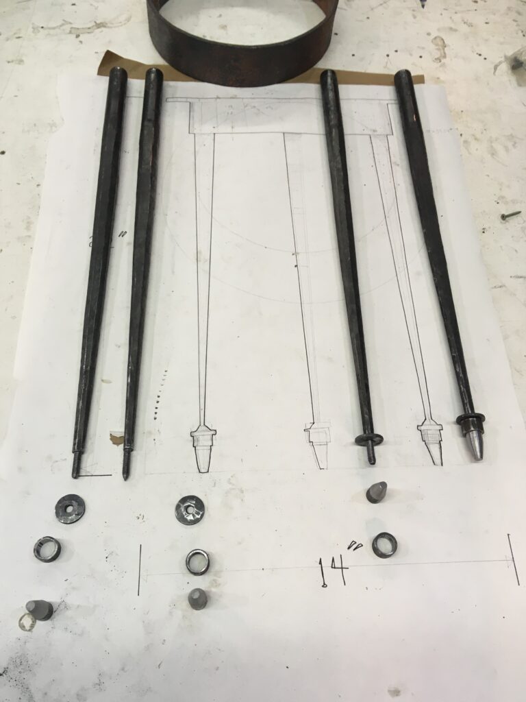 Forged tapered table legs and fittings laid out on a drawing